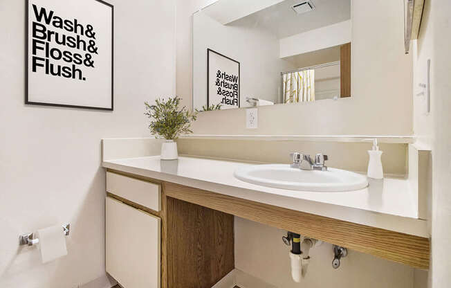 A bathroom with a large counter and mirror at South Bridge Apartments in Fort Wayne, IN