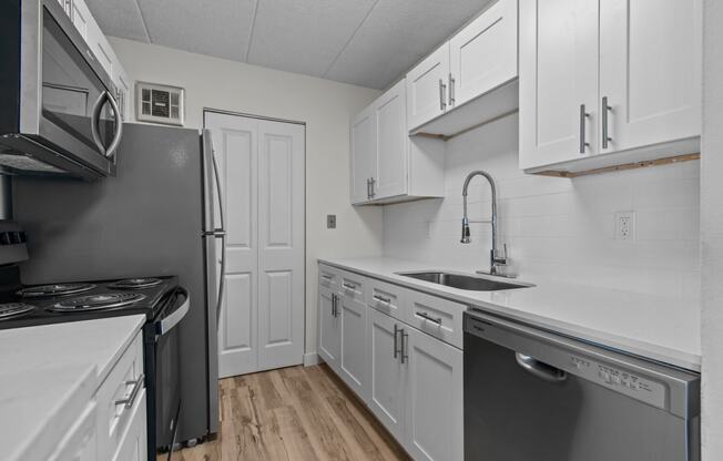 an empty kitchen with white cabinets and stainless steel appliances