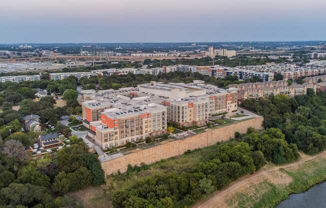 A large building with a red roof is surrounded by a wall and trees.
