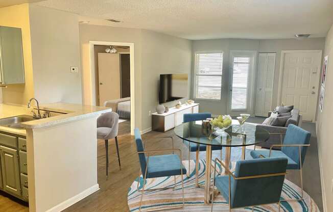a living room and kitchen with a glass table and chairs at Aqua Bay Apartments in Naples, FL 34116