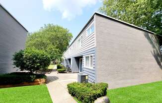 the exterior of a gray building with a sidewalk and grass