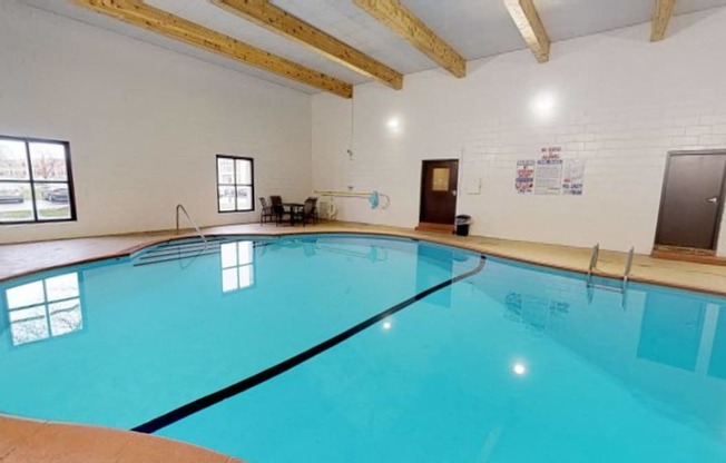 the indoor pool is spacious and has a ceiling with exposed beams