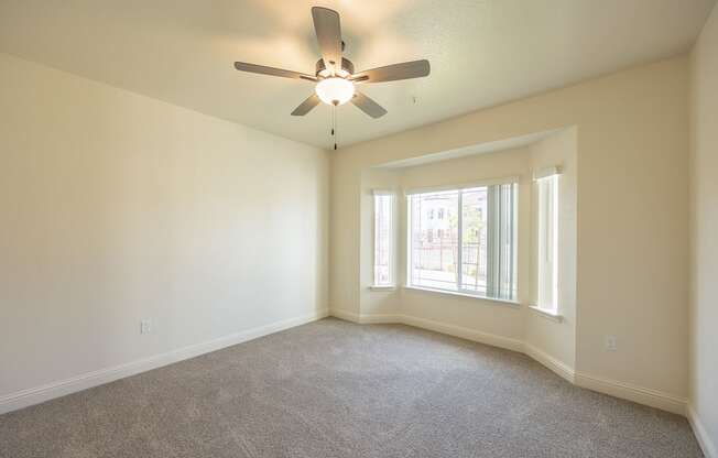 A room with a ceiling fan and carpeted floor.