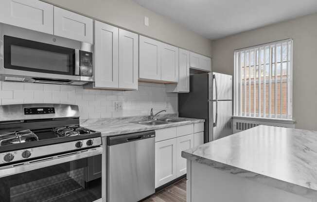 an all white kitchen with stainless steel appliances and marble counter tops