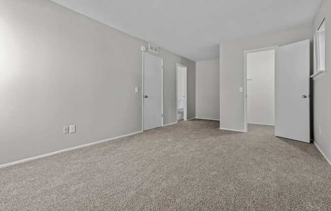 the living room of an apartment with carpeting and white doors