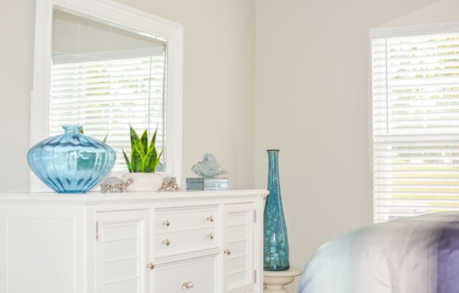 a white dresser with a mirror and blue vases on it