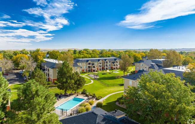 an aerial view of an apartment complex with a green lawn and a pool