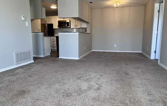 A spacious living room with a kitchen in the background.