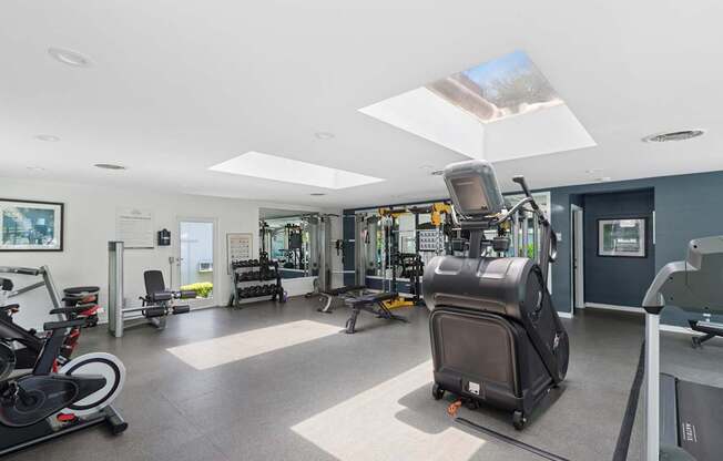A gym with a variety of equipment including a treadmill, stationary bike, and weight machines.
