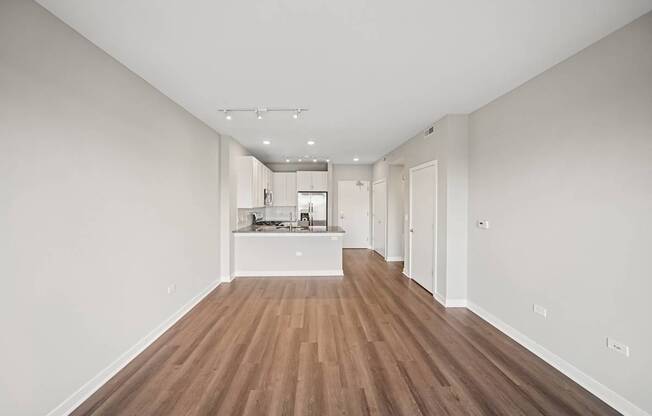 A long, empty hallway with wooden floors and white walls.