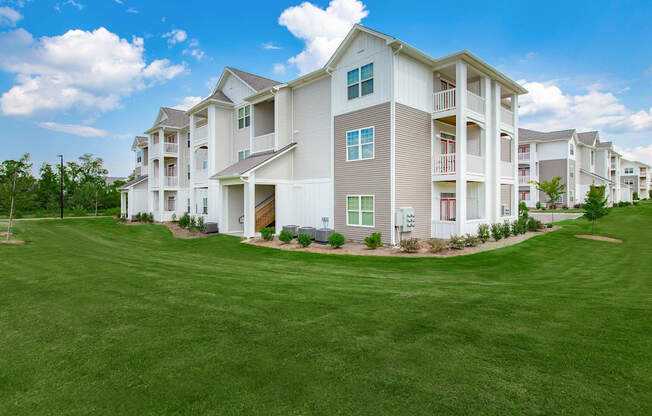 A large white apartment building with a green lawn in front.