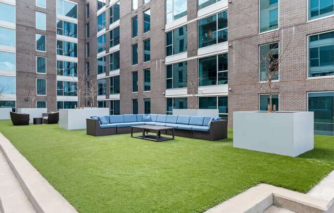 an outdoor lounge area with couches and a table in front of an apartment building