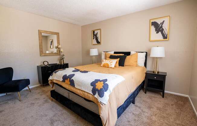 A bedroom with a bed, chair, and two lamps.