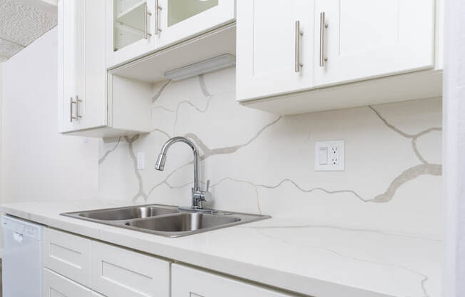 a white kitchen with a sink and white cabinets