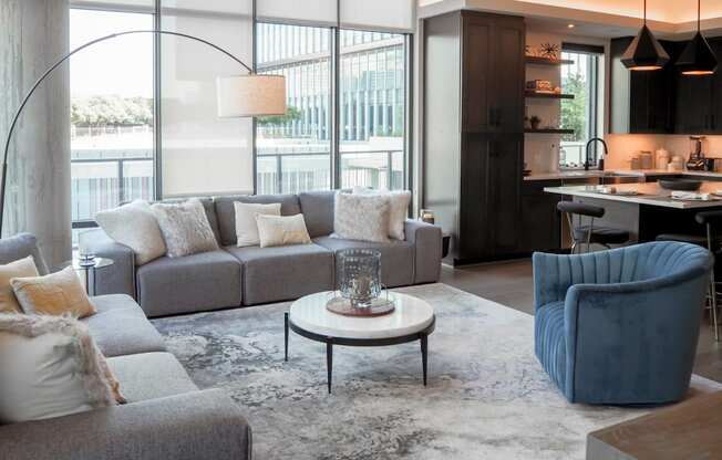 3-bedroom model living room with a gray couch and a blue chair at The Hamilton apartments in Dallas, TX