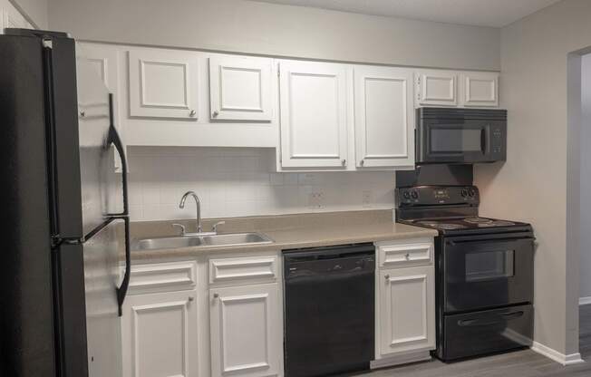 a kitchen with white cabinets and black appliances