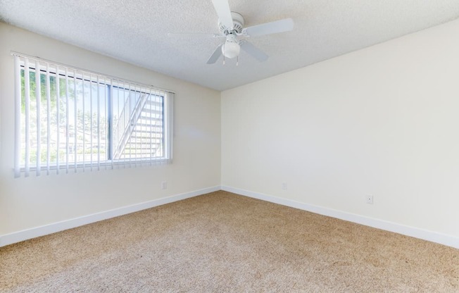 a bedroom with a ceiling fan and a window  at Redlands Park Apts, Redlands, CA, 92373