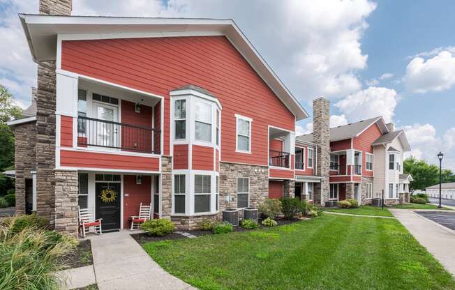 a row of red apartment buildings with grass and a sidewalk