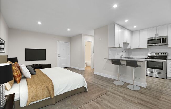 a bedroom with a bed and a kitchen
