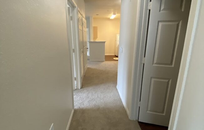 a hallway with a door open to a room and a kitchen