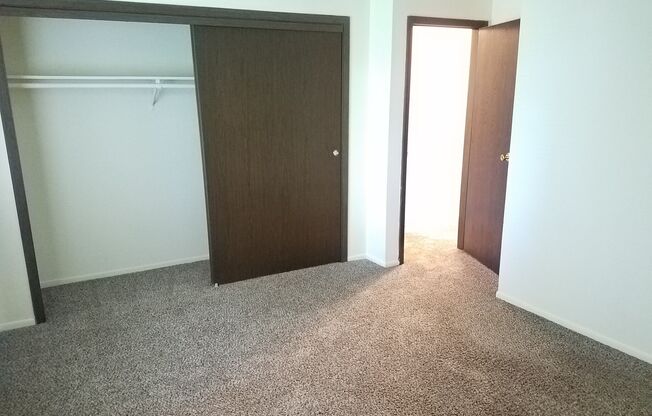 A room with a brown door and a grey carpet.