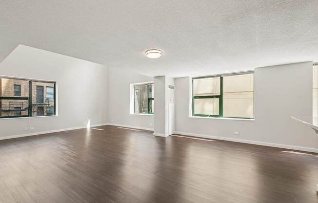 A spacious room with wooden floors and white walls.