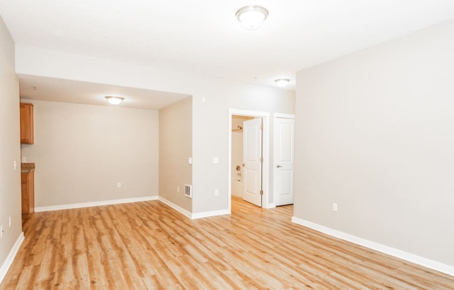 an empty living room with wood flooring and white walls