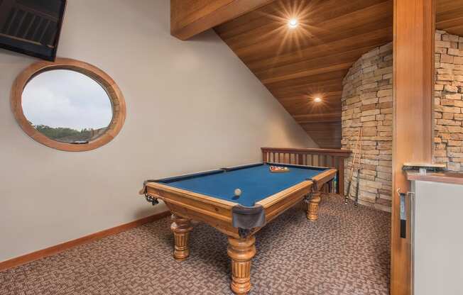 a pool table in a cabin with a porthole at Lodge of Overland Park Apartments, Kansas