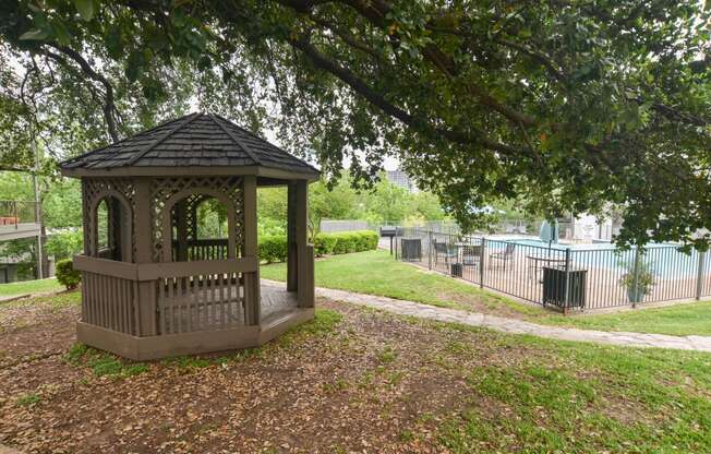 a gazebo in a park next to a pool