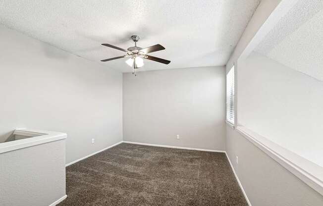 A room with a ceiling fan and carpeted floor.