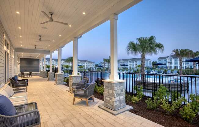 a covered porch with a view of the water and palm trees