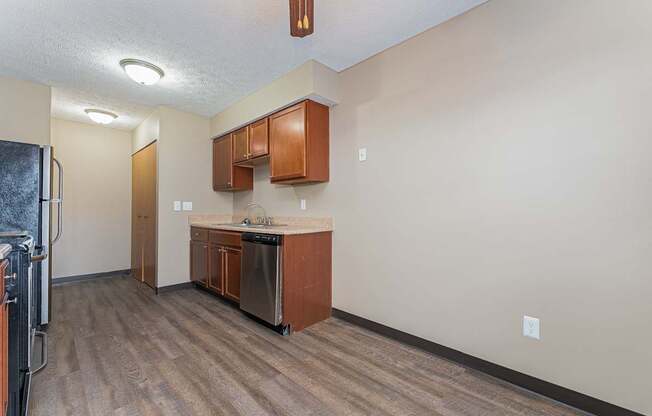 A kitchen area with wooden floors and brown cabinets