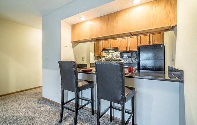 Renovated kitchen with dark counter tops and seating at the counter at Fountain Glen Apartments