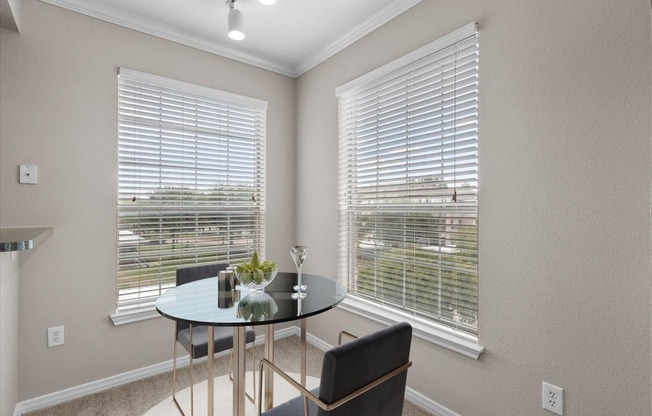 a dining room with two windows and a table with two chairs