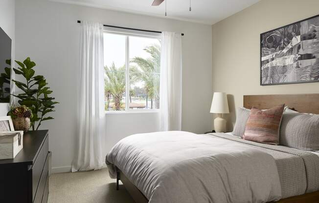 a bedroom with a bed and a window with white curtains