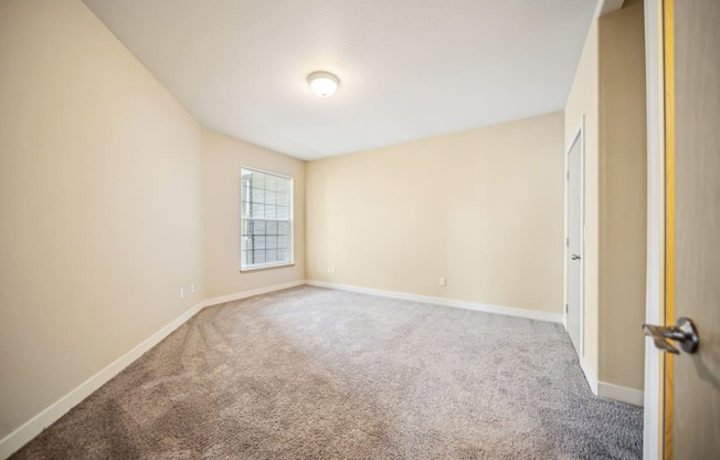 A room with a carpeted floor and a door on the right side.