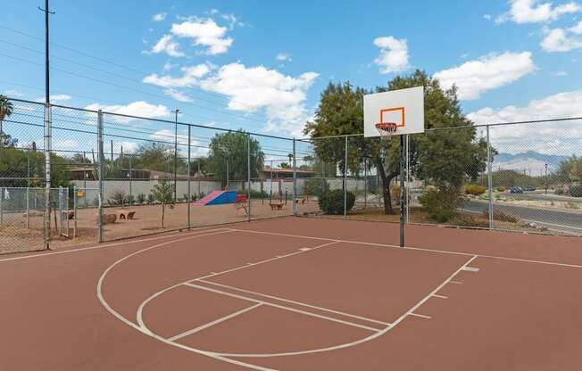 A basketball court with a basketball hoop and a fence surrounding it.
