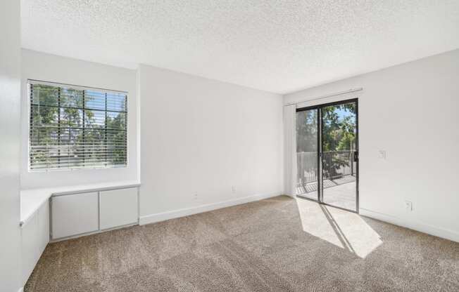 an empty living room with a sliding glass door to a patio