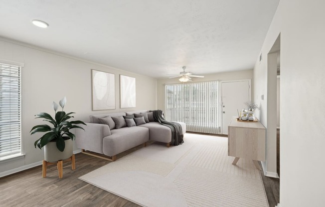 a living room with a gray couch and a white rug at Woodlands of Plano Apartments in Plano, TX