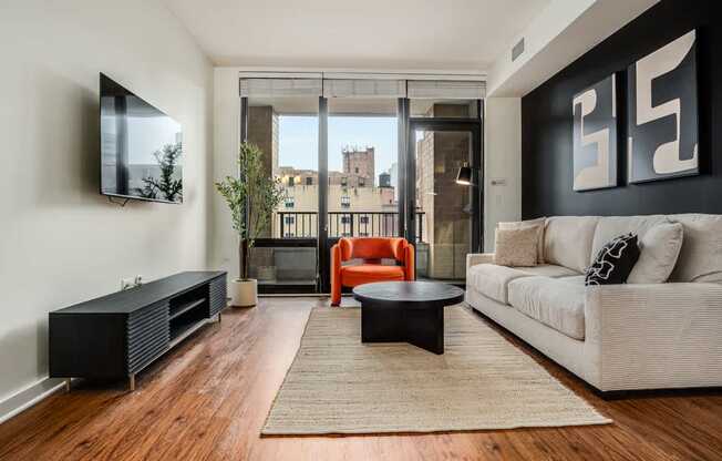 A living room with a white couch, a black coffee table, and a flat screen TV mounted on the wall.