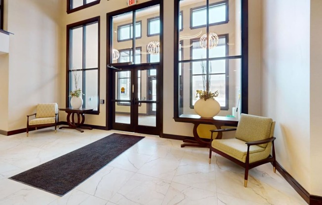 a lobby with large windows and chairs and a rug
