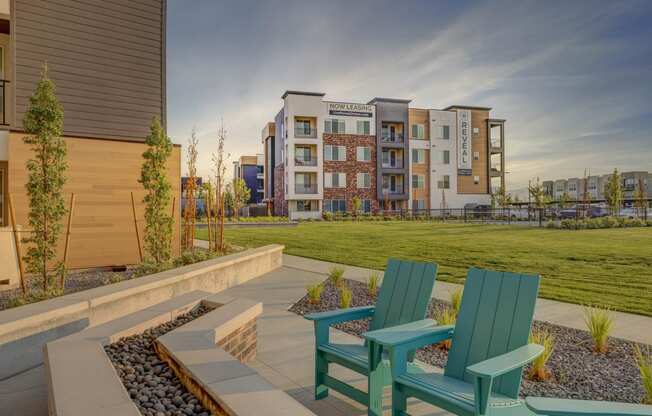two green chairs on a patio with an apartment building in the background