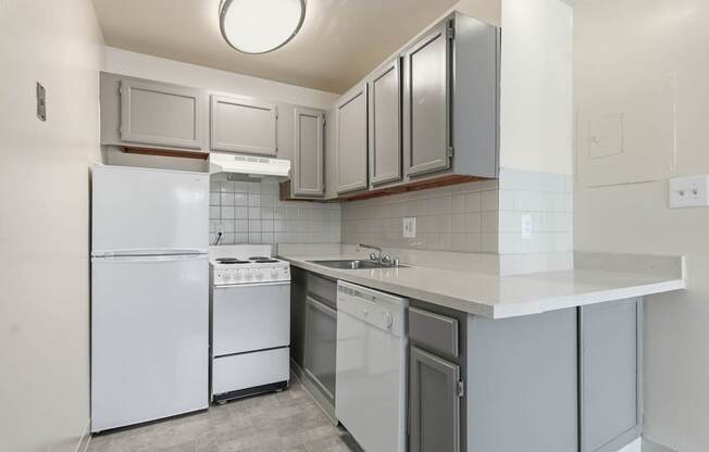 A kitchen with white appliances and grey cabinets.