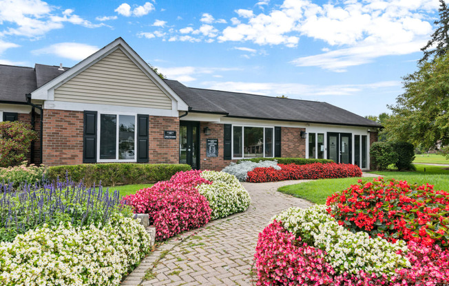 a brick house with a brick walkway and colorful flowers in front of it