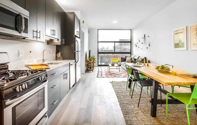 a kitchen with stainless steel appliances and a wooden table with green chairs