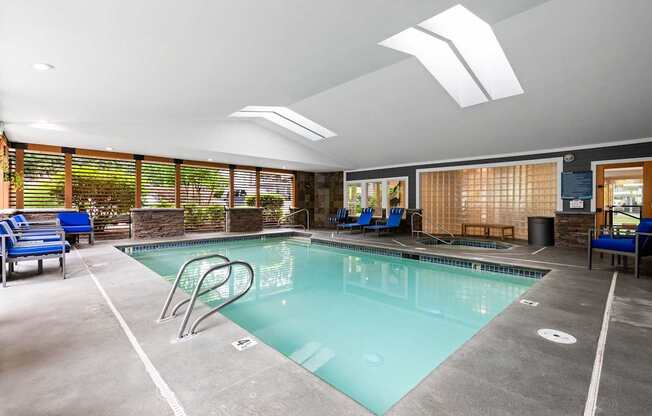 A large indoor swimming pool with a diving board and lounge chairs.