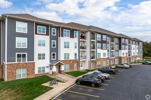 a large apartment building with cars parked in a parking lot