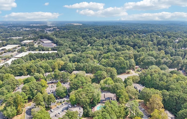 A bird's eye view of a forested area with buildings and roads.