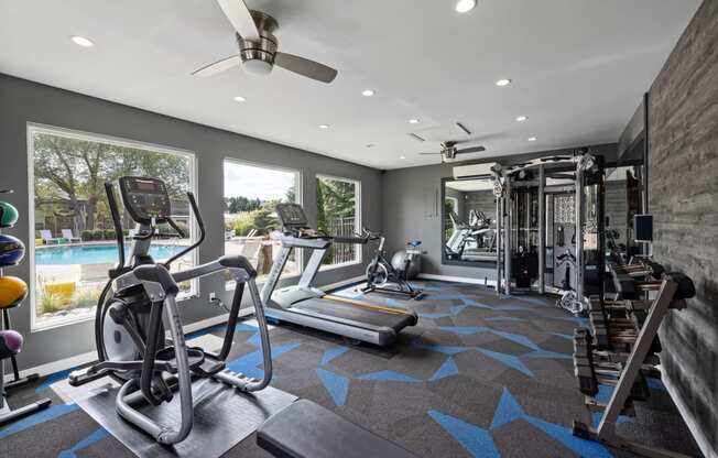 a gym with exercise equipment and a pool in the background