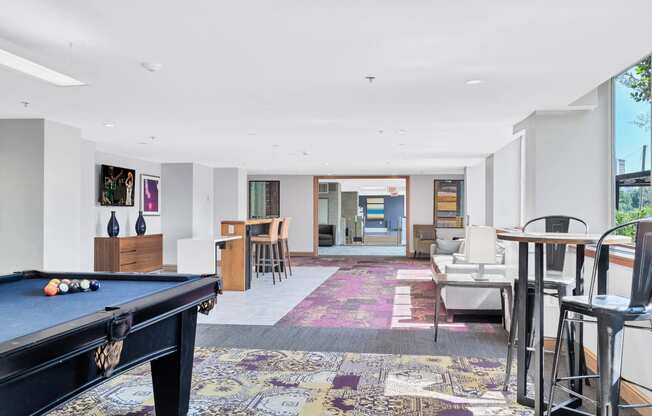 a living room with a pool table and a dining room with tables and chairs